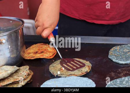 Atontonilco, Mexiko - 29. Mai 2016: Eine Person kocht blaue Maistortillas auf einem flachen Grill, mit einem Spachtel, um sie an Kunden zu verkaufen. Stockfoto