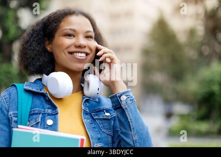 Nahaufnahme Porträt einer fröhlichen afroamerikanischen Studentin, die am Handy spricht Stockfoto