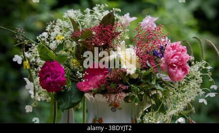 Ein wunderschöner Blumenstrauß aus Gartenblumen und Rosen in einer Vase. Stockfoto