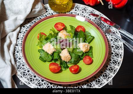 Farbenfroher grüner Salat mit panierten Hähnchenstücken und Kirschtomaten, serviert auf einem lebendigen Teller, gesundes Mittagskonzept. Stockfoto