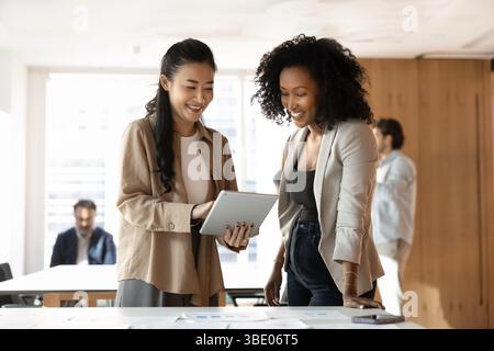 Zwei weibliche Kollegen arbeiten im Büro mit einem Tablet zusammen Stockfoto