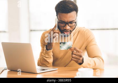 Afrikanischer Mann am Telefon sprechen Holding Kreditkarte Stockfoto