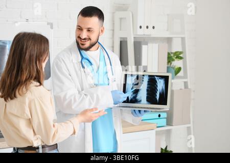 Männlicher Arzt zeigt Röntgenaufnahme der Lunge auf Laptop an Patienten in der Klinik Stockfoto