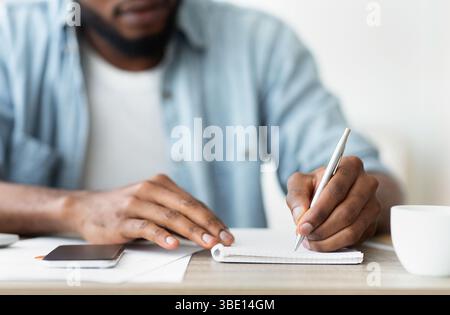 Afrikanische amerikanische Geschäftsmann aufschreiben, um seine Pläne zu Notepad Stockfoto