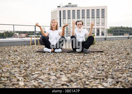 Seniorenpaar meditiert auf dem Dach und übt Achtsamkeit und Entspannung Stockfoto