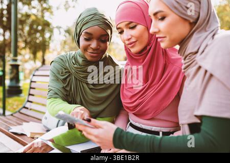 Muslim Female Zeigt Pädagogische Anwendung Auf Smartphone, Um Freunde Im Freien Stockfoto