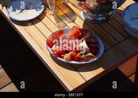Eine wunderschön angeordnete, ausgewählte Charcuterie-Platte, die elegant auf einem Holztisch präsentiert wird Stockfoto