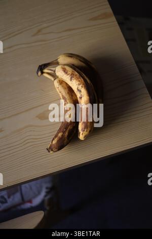 Top-down-Schuss von drei Reifen Bananen auf einem rustikalen Tisch. Stockfoto
