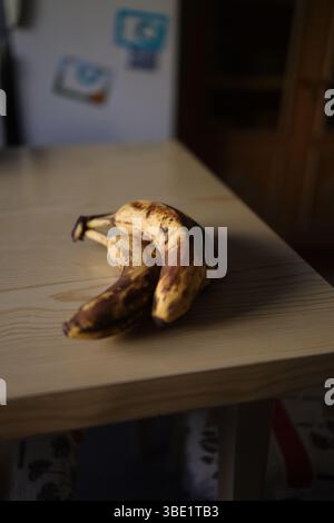 Drei gelbe Bananen auf einem rustikalen Holztisch. Stockfoto