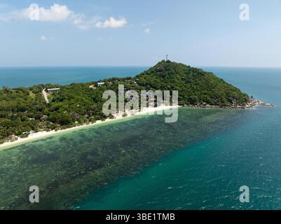 Ein landschaftlich schöner Hügel mit üppigem Grün und Häusern mit Blick auf ein ruhiges türkisfarbenes Meer. Leela Beach. Ko Pha Ngan, Thailand. Stockfoto