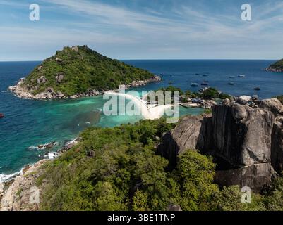 Felsige Klippen umgeben von üppigem Grün mit Blick auf türkisfarbenes Wasser unter sonnigem Himmel. Ko Nang Yuan, Thailand. Stockfoto