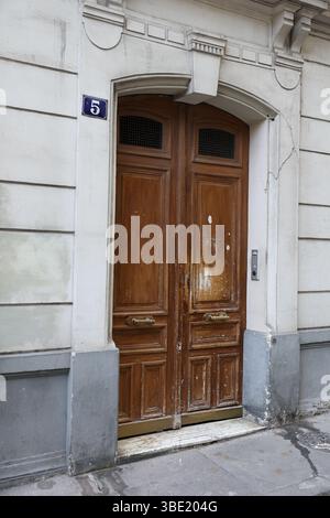 Verwitterter gewölbter Pariser Holzeingang Nr. 5 mit abblätternder Farbe Stockfoto