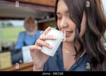 Eine indonesische südostasiatische Frau genießt Kaffee vor dem Café. Ein kleines Unternehmen in einem Café oder Café auf einem Lkw Stockfoto