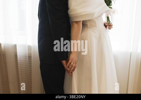 Die Braut und der Bräutigam halten die Hände während der Heiratserteilung auf weißem Hintergrund. Nahaufnahme. Stockfoto