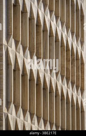 Geometrische Betonfassade mit sich wiederholenden architektonischen Details und starken Schatten. Modernes Gebäude außen, brutalistisches Design, städtische Struktur, Abstr Stockfoto