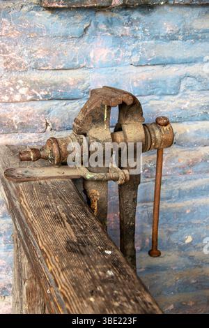 Alter rostiger Schraubstock auf einer Holzwerkbank Stockfoto