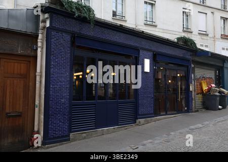 Modernes Blue Brick Restaurant an der schrägen Pariser Kopfsteinpflasterstraße mit historischen Gebäuden Stockfoto