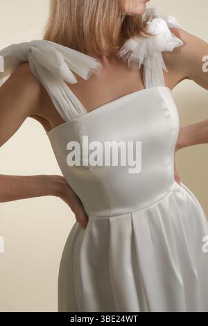 Serie von Studiofotos eines weiblichen Models in elegantem weißem Midikleid mit Schleifen an den Schultergurten Stockfoto