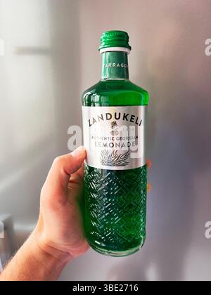 Kiew, Ukraine - 26. Mai 2025: Nahaufnahme einer Person mit einer dekorativen grünen Flasche Zandukeli Estragon Limonade. Stockfoto