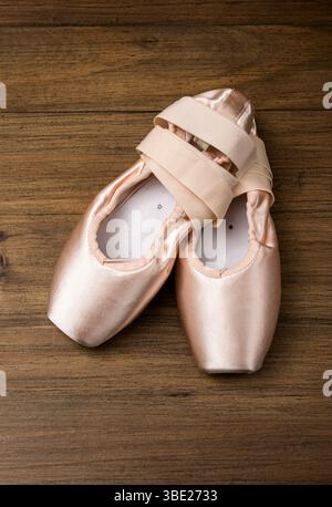 Ballett-Satin spitzenschuhe mit Bändern auf Holzboden, die Eleganz und Eleganz vermitteln Stockfoto