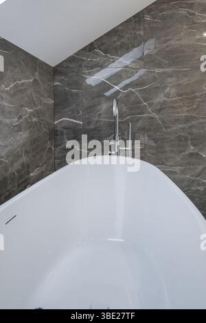 Modernes Bad mit weißem Waschbecken auf Holzarbeitsfläche, Glasdusche mit Regentropfen und eleganten grauen Wänden. Stockfoto