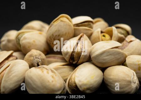 Geröstete Pistazien in der Schale auf schwarzem Hintergrund (Antep Fistigi), gegossene geröstete Erdnüsse (Pistazien) Stockfoto