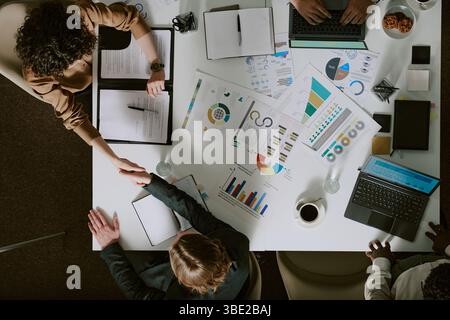 Treffen mit verschiedenen Teammitgliedern, um Geschäftsdaten zu analysieren und Strategien für das Unternehmenswachstum zu diskutieren. Verschiedene Diagramme, Dokumente und Geräte in der Tabelle Stockfoto