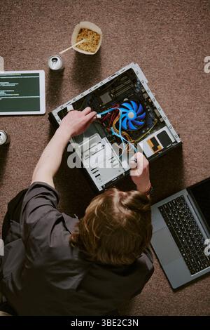 Techniker, der Computer-Hardware mit offener CPU und sichtbarem Lüfter in verschiedenen Werkzeugen und Geräten handhabt. Top-Down-Ansicht, in der technische Fähigkeiten gezeigt werden Stockfoto