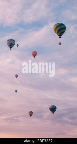 Farbenfrohe Heißluftballons, die durch den rosa Himmel von Kappadokien, Türkei, schweben Stockfoto