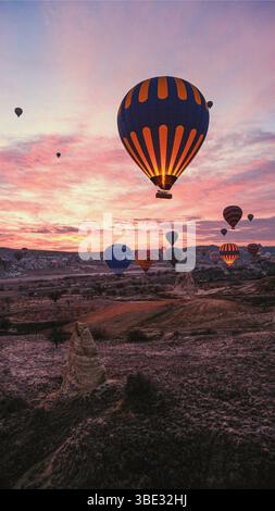 Wunderschöne Heißluftballons, die während eines Sonnenaufgangs im Januar 2025 über den Bergen von Kappadokien in der Türkei schweben. Stockfoto