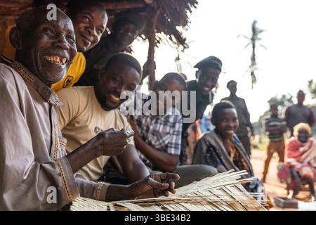 Tansania, Kimbanda WMA, in einem Dorf, webt ein alter Mann Palmblätter unter den Augen von Rangern und Beamten der WMA (Wildlife Management Area) Stockfoto
