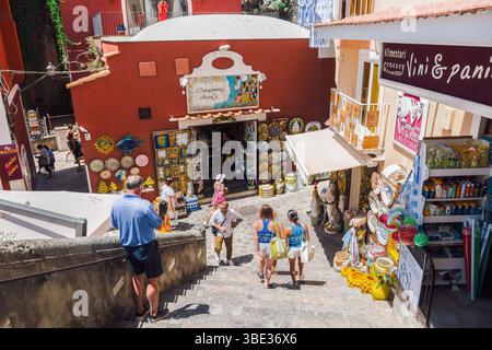 Positano, Italien Besucher schlendern an einem sonnigen Tag an der Amalfiküste die Stufen hinunter und bummeln durch farbenfrohe Geschäfte mit Keramik. Stockfoto