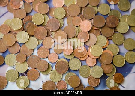 Verstreute Euro-Cent-Münzen in warmen Gold-Rot-Tönen - Stückelungen von 1, 2, 5 und 10 Cent - bilden einen reichen, strukturierten Hintergrund Stockfoto