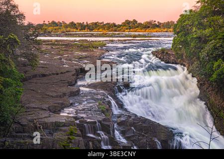 Simbabwe, die septentrionale Provinz Matabeleland, der Bezirk Hwange, der Victoria Falls National Park, der Zambezi River am UNESCO-Weltkulturerbe Victoria Falls, hier Devil's Falls am Ende der Trockenzeit bei Sonnenuntergang. Stockfoto