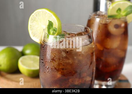 Leckerer Cuba Libre Cocktail in Gläsern und Limetten auf dem Tisch, Nahaufnahme Stockfoto