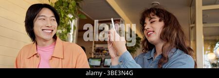 Junge Freunde genießen die Gesellschaft des anderen und halten fröhliche Erinnerungen in einem lebhaften Café fest Stockfoto