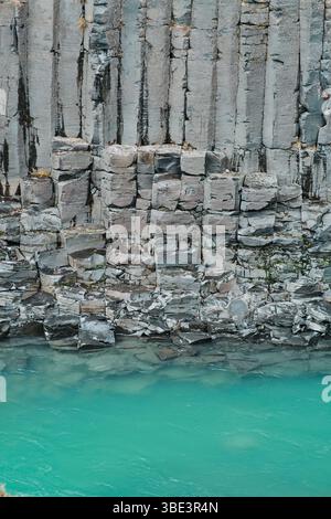 Nahaufnahme der Basaltsäulen und des türkisfarbenen Flusses im Studlagil Canyon, Island. Stockfoto