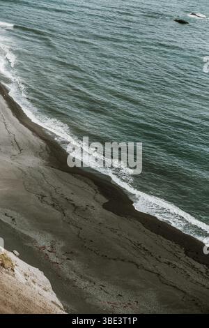 Wellen schlagen sanft gegen die schwarze Sandküste von Fauskasandur, Island. Stockfoto