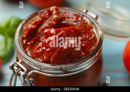 Leckere sonnengetrocknete Tomaten im Glas auf hellblauem Tisch, Nahaufnahme Stockfoto