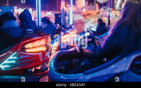 Freunde genießen Autoscooter bei einem lebhaften Winterkarneval bei Nacht Stockfoto