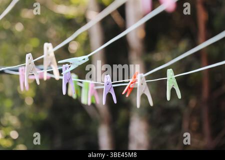 Farbenfrohe Kleiderschalen in der Linie. Hängende Haken im Garten. Wäschetrocknungskonzept. Blick auf die Wäscheleine im Freien. Haushaltsdetails. Home Routine Szene. Stockfoto