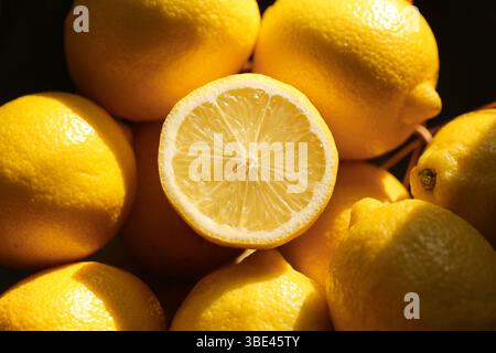 Ganze Zitronen in Sonnenlicht getaucht. Hellgelbe Zitrusfrüchte mit natürlichen Schatten. Frische Bio-Produkte. Tropisches Aroma und gesunde Zutat. Stockfoto