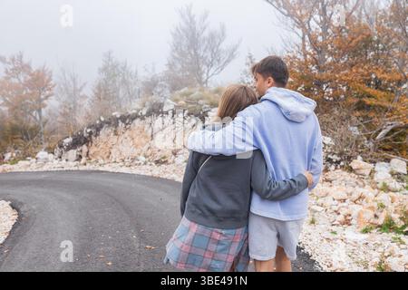 Ein Paar, das auf der Herbststraße durch Bergnebel blickt Stockfoto