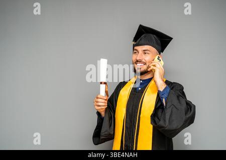 Glücklicher Absolvent, der nach der Abschlussfeier einen Anruf macht Stockfoto