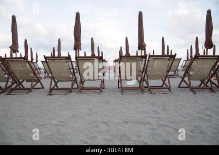 Eine Reihe von Liegestühlen steht auf dem Sand Stockfoto