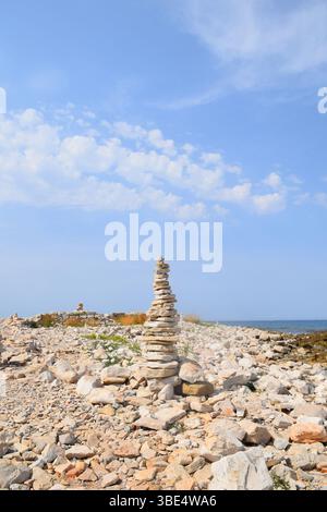 Sorgfältig ausbalancierter Felsenhain, Turm an einem felsigen Strand unter einem klaren blauen Himmel. Der Steinstapel, Harmonie, Achtsamkeit und natürliches Gleichgewicht. Trockenes Gelände. Stockfoto