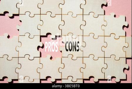 Symbol für Pro vs. Cons. Konzeptwort Pros vs. Cons on Holzpuzzle. Schöner rosafarbener Hintergrund. Business und Pro vs. Cons Konzept. Kopierbereich Stockfoto
