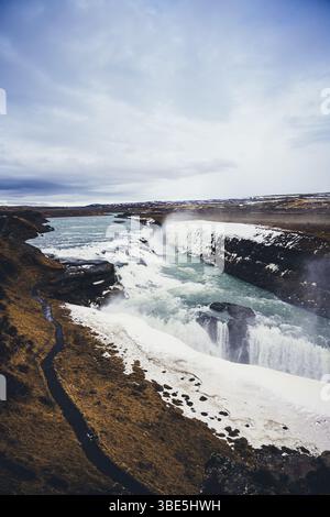 Eine atemberaubende Schönheit des Gullfoss Wasserfalls in Island. Die mächtige Kaskade fließt über zerklüftete Klippen, umgeben von atemberaubenden Eislandschaften und Dynam Stockfoto