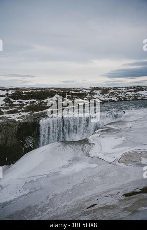 Faszinierender Blick auf den Dettifoss Wasserfall in Island, teilweise gefroren und umgeben von einer schneebedeckten Landschaft. Die Kraft und Schönheit der Natur sind an Stockfoto
