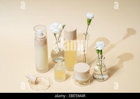 Eine vollständige Ausstellung verschiedener Kosmetikbehälter mit weißen Blumen in Laborflaschen und -Zylindern, die eine saubere und ausgewogene Schönheitsästhetik auf einer ne darstellen Stockfoto